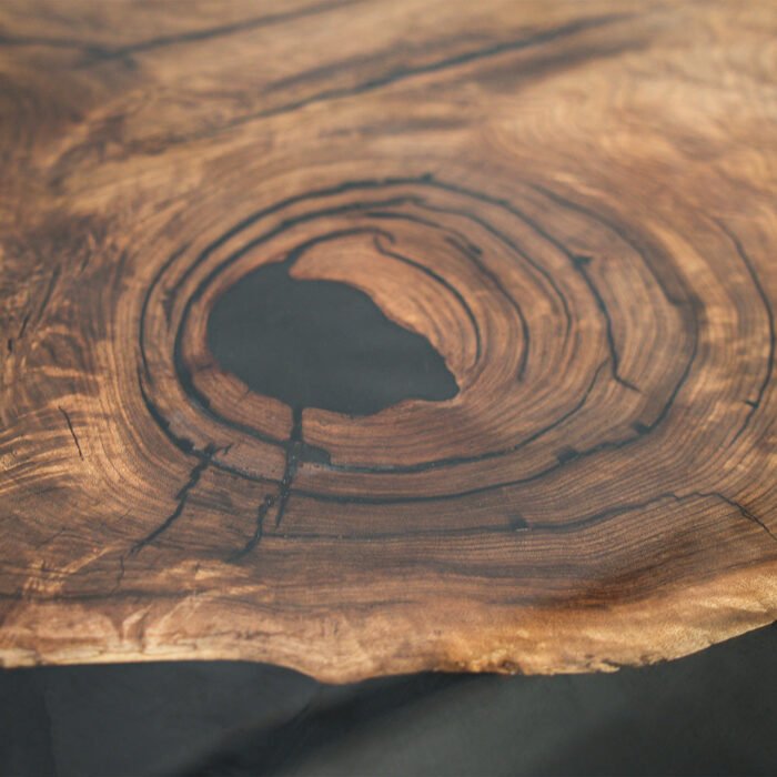 Angled view of the Sylva Home custom black walnut dining epoxy resin river table, model ET9, showing the table’s depth and texture.