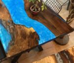 Angled view of the Sylva Home custom black walnut epoxy river dining table tops, model ET28, showcasing its overall aesthetic.