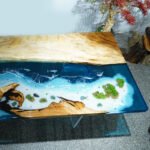 Side view of the Sylva Home custom epoxy resin ocean table, model ET55, showcasing the table's edge and legs.