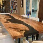 Side view of the Sylva Home custom walnut epoxy resin river dining table, model ET43, showcasing the table's edge and legs.