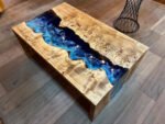 Angled view of the Sylva Home custom epoxy blue river waterfall table, model ET62, showcasing its overall aesthetic.